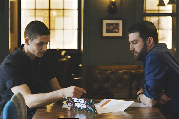 Image of Tyler, a Greene King chef and ex-offender, sitting at a pub table opposite his assistant manager Sam Calver, discussing work.