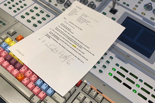 A white piece of A4 paper covered in unintelligible writing. This is the script for the radio advert. Scribbles and corrections are visible written in the margins. The paper is placed on top of a recording studio’s control dashboard with multicoloured buttons