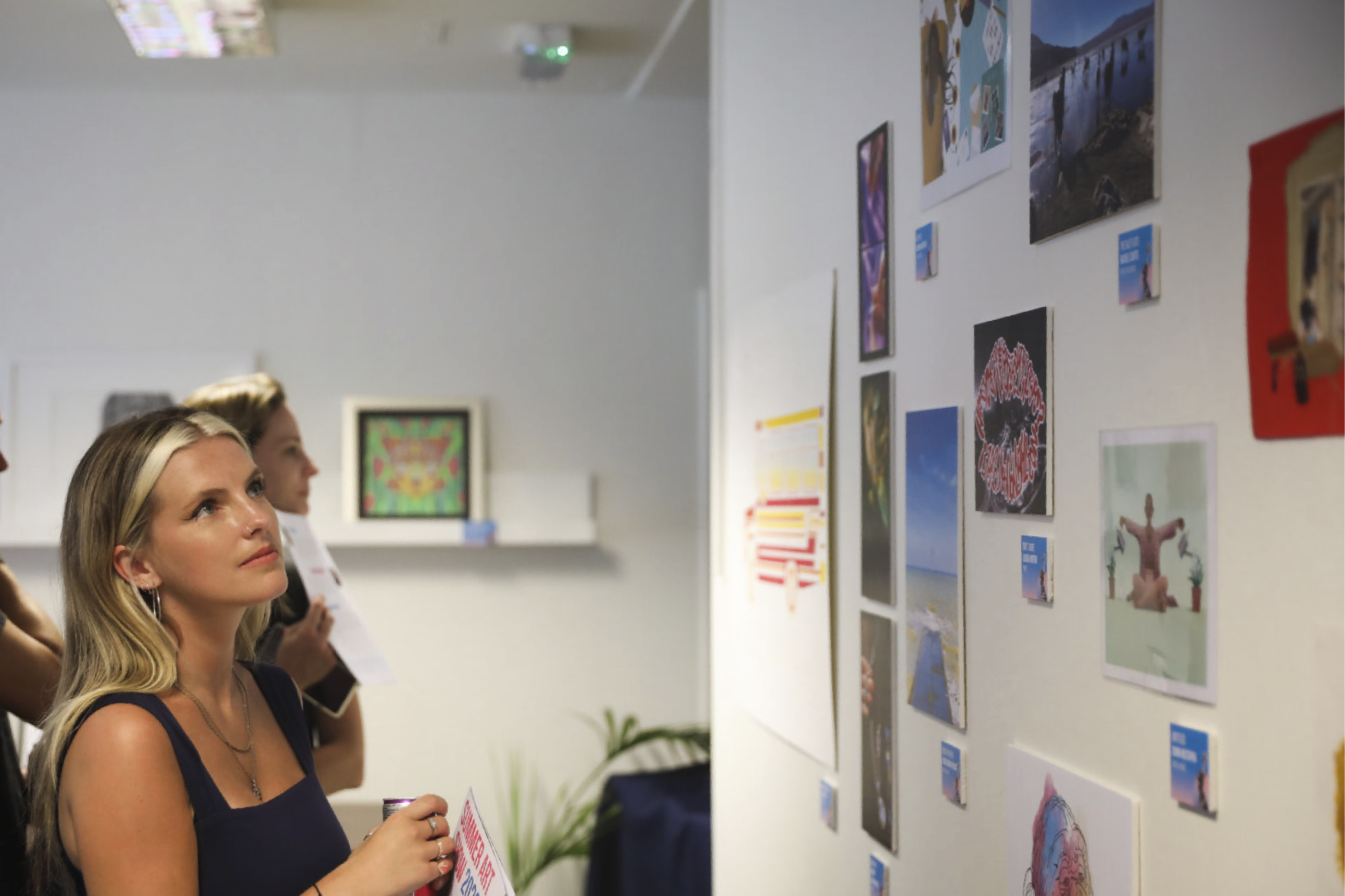 Spectator viewing the wall-mounted submissions to the Design102 art show.