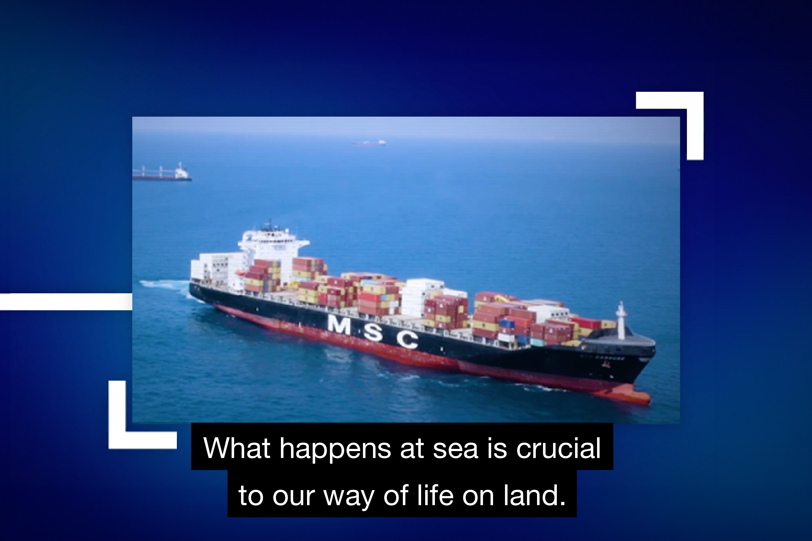 Screenshot of a video featuring an inset image of a cruising cargo ship at sea. Closed captions beneath the image detail the dialogue: “What happens at sea is crucial to our way of life on land.”